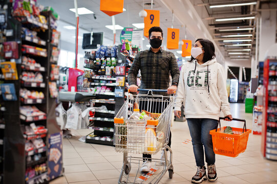 Asian couple wear in protective face mask shopping together in supermarket during pandemic.