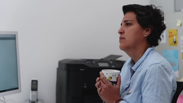 latino woman is being thoughtfull while drinking coffee at the office