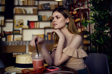 Pretty woman sits at a table in a restaurant having fun and relaxing glass with a drink