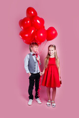 Valentines day. Two happy children with heart shape air balloons on pink background