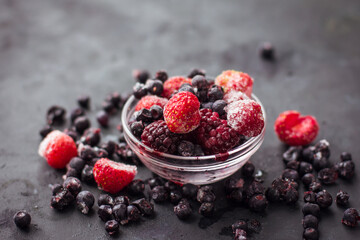 Close up of frozen mixed fruits and berries on a black table  Healthy food vitamins snack dessert