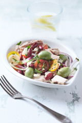 Salad with tuna, green olives and cherry tomatoes. Bright wooden background. Close up. 