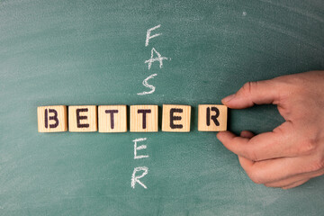 Better and Faster concept. Text from letters of the wooden alphabet on a green chalk board