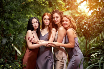 four sensual ladies in elegant silk dresses in the forest, beautiful women with healthy radiant...