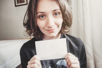 girl smiles while holding a paper with her hands