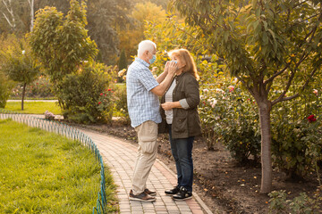 Obraz premium Senior couple walking outside wearing medical masks