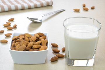Freshly prepared almond milk in a glass cup with dried almond nuts