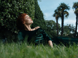 Naklejka na ściany i meble Elegant woman lies on the grass outdoors nature luxury decoration
