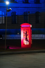 Red phone booth with woman figure inside.