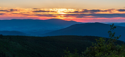 Sunset with hills, colorful sky and clouds from Dlouhe strane hill in Jeseniky mountains in Czech republic