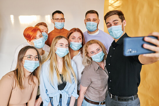 people in medical masks take photo on smartphone, careful crowd of people of caucasian ethnicity using face facial sterile masks, smile at camera of mobile phone