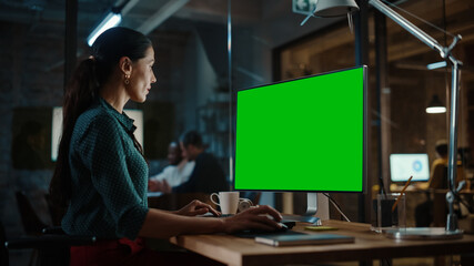 Middle Aged Multiethnic Specialist Working on Desktop Computer with Green Screen Mock Up Display in...