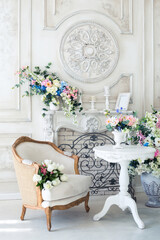 Bright luxury white and blue colored interior living room with flowers in vases. the walls are decorated with baroque ornaments