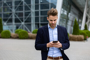 Handsome businessman using smartphone and smiling. Happy young man using mobile phone apps, texting message, browsing internet, looking at smartphone. Young people working with mobile devices.