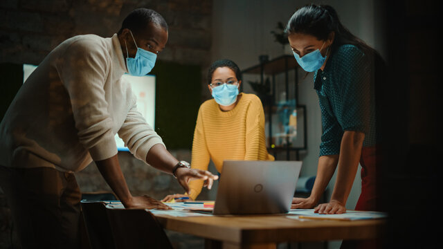 Diverse Multiethnic Team Wearing Face Masks During a Meeting Room Conversation Behind Glass Walls in Creative Office. Social Distancing Restrictions Concept in Work Place During Coronavirus Pandemic. - Powered by Adobe