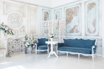 Bright luxury white and blue colored interior living room with flowers in vases. the walls are...