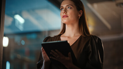 Portrait of a Young Creative Caucasian Female with Dark Hair Using a Tablet Computer in Evening Dress or Blouse. Beautiful Diverse Independent Woman is Browsing Internet and Chatting in Messenger.