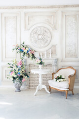 Bright luxury white and blue colored interior living room with flowers in vases. the walls are decorated with baroque ornaments
