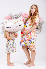 happy pregnant woman with little daughter in colorful dresses on flower wall background
