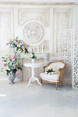 Bright luxury white and blue colored interior living room with flowers in vases. the walls are decorated with baroque ornaments