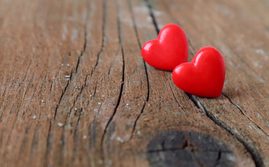 Fototapeta premium Two red hearts on a wooden background, a crack in the center, a side view, a close-up-the concept of a complex family relationship