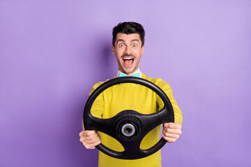 Portrait of brunet impressed guy hold wheel wear yellow sweater isolated on pastel lilac color background