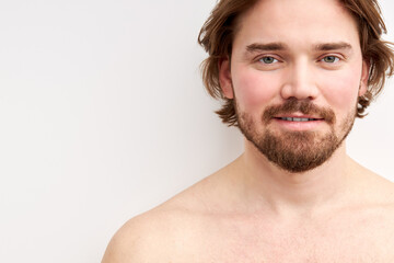 Obraz premium smiling shirtless man having bristle looking at camera, young caucasian male model isolated over white background