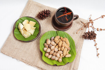 Bogor beans (Vigna subterranea), peanuts (Arachis hypogaea L.) and cassava are served on a woven plate and banana leaves on a white background. isolated