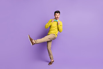 Fototapeta na wymiar Full size profile photo of brunet optimistic guy dance wear yellow sweater trousers sneakers isolated on lilac background