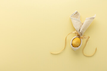 Abstract easter bunny from napkin and golden painted egg on yellow background, easter festive concept