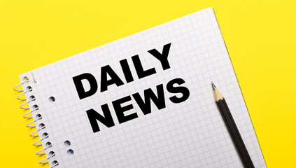 White notebook with DAILY NEWS written in black pencil on a bright yellow background.
