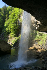 Mighty beautiful waterfall taken from a cave, between Glarus and Klausenpass in the Swiss Prealps