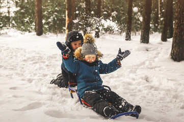 Fototapeta na wymiar Two boys play in the snow in a beautiful winter forest.