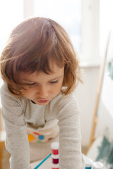 Fototapeta premium Child painting her hand with paint and paintbrush. Art therapy for children.