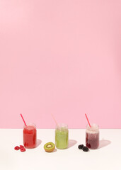 Summer colorful fruit smoothies in jars on pink background. Healthy, detox and diet food concept. Copy space