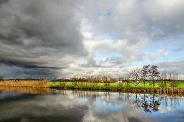 Dark clouds in a dramatic sky over the green polders between Schipluiden and Vlaardingen, The Netherlands on a winter afternoon