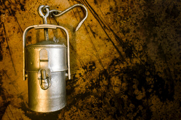 Old miner safety carbide lamps on a dark grunge background with empty space. Vintage acetylene lantern, retro gas-collection lamp used in 1920's. Collectible item. 