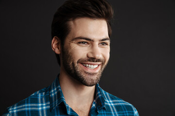 Joyful handsome brunette guy smiling and looking aside