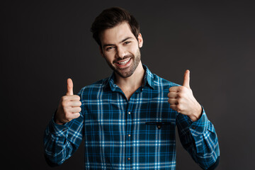 Joyful handsome guy smiling and showing thumbs up