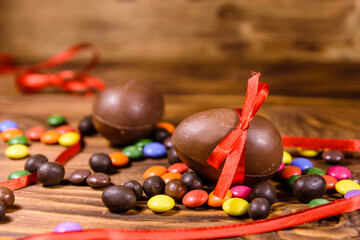 Chocolate easter eggs and multicolored candies on wooden table