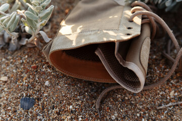 Army beige military style shoe on the laces lies on a background of sand and grass, the concept of outdoor
