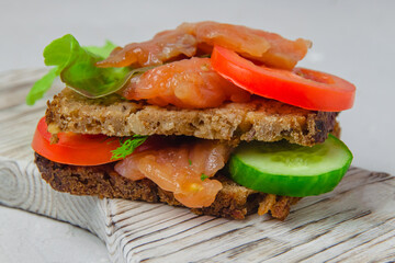 Trout bread snack with salad, vegetables and herbs laying on a white rustic board