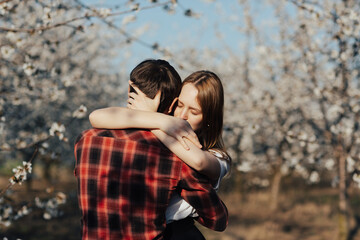 Beautiful tender couple in love cuddling in a blooming garden. 