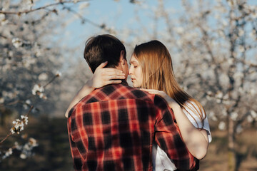 Fototapeta premium Stylish lovers near the blossoming trees at engagement. Concept of spring, love and tenderness.