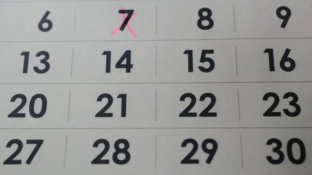 hand crossing a pink marker out days on wall calendar