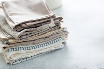 Clean kitchen textiles made of cotton and linen - napkins, towels folded on the table, horizontal,...