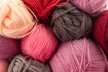 Background from multi-colored balls of threads for knitting. Pink, orange, red, purple, violet, gray colors. Woolen thread.