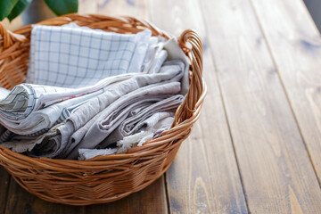 Kitchen textiles made of cotton and linen - napkins, towels in a wicker willow basket with two...