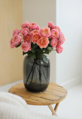 Beautiful pink spray roses in big vase. Fresh bouquet go pink roses at home. Cozy interior.