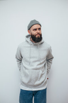 Handsome hipster guy with beard wearing gray blank hoodie with space for your logo or design. Mockup for print
